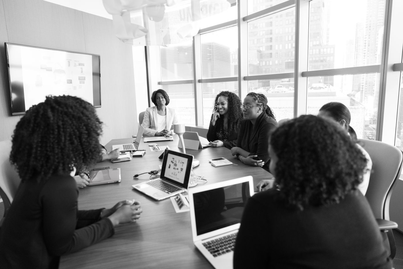 Des femmes échangent autour d’une table de réunion, ordinateurs et carnets ouverts